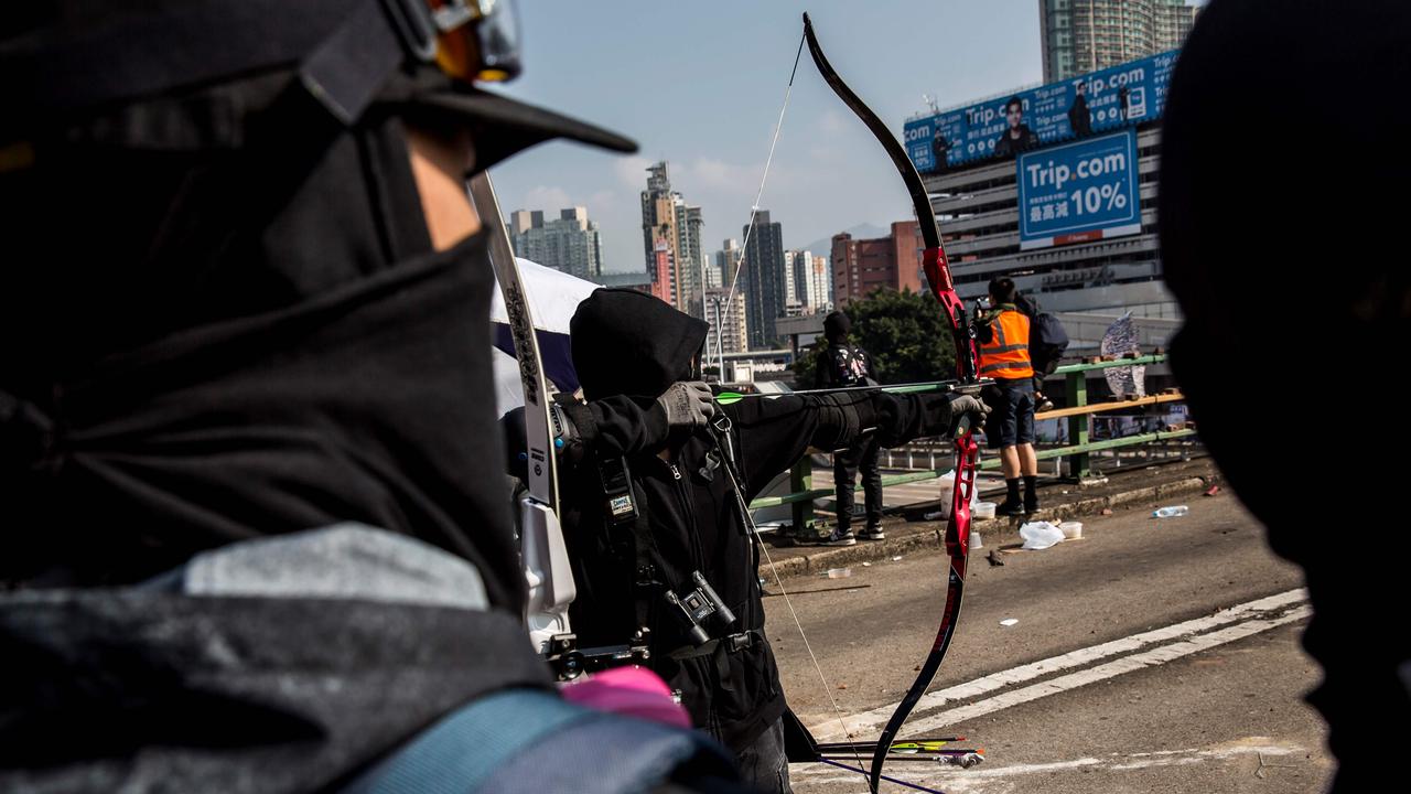 A protester uses a bow and arrow while standing on a barricaded street outside The Hong Kong Polytechnic University. Picture: ISAAC LAWRENCE / AFP.