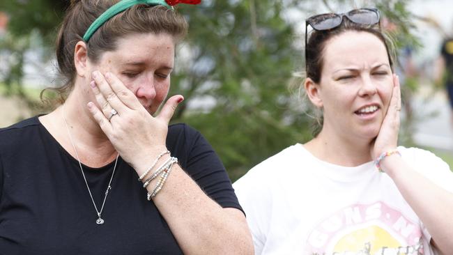 Shae Curr-Parkes and Kate Hammacott become distressed as they wait for word from family members stranded by flood waters at Holloways Beach. Picture: Brendan Radk