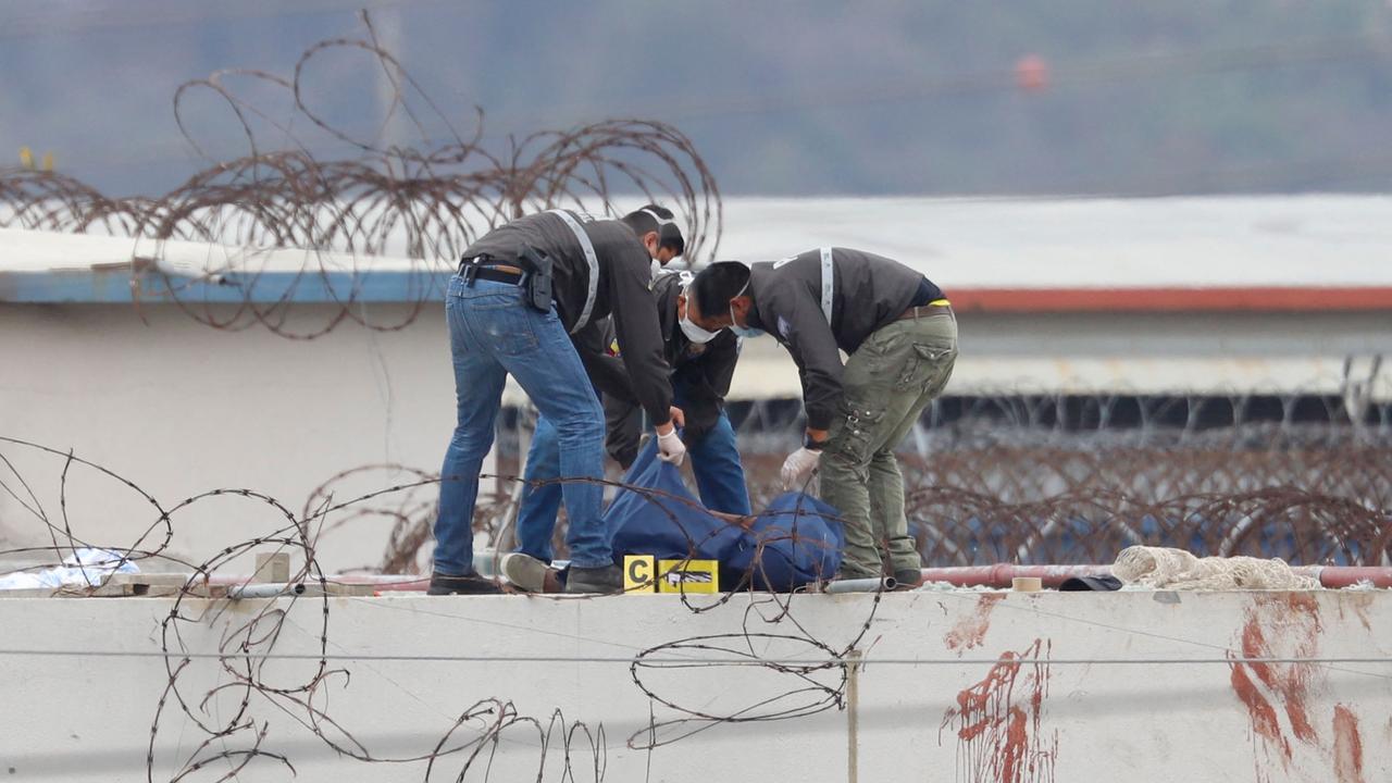 Members of the Ecuadorean police remove the body of an inmate on the roof of a pavilion of the Guayas 1 prison in Guayaquil, Ecuador. (Photo by Nicola Gabirrete / AFP)