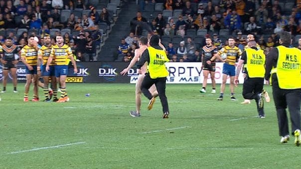 Players watch on as security guards chase Cooper, who has since been sacked from his radio job. Picture: AAP/Joel Carrett