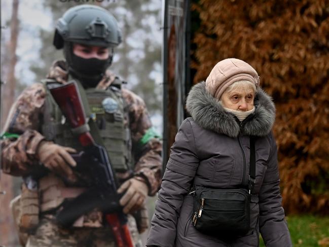 An elderly woman walks past a placard promoting enlistment in the military in Kyiv on December 22, 2024, amid the Russian invasion in Ukraine. Picture: AFP