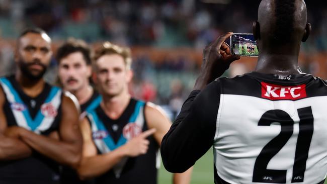 ADELAIDE, AUSTRALIA - APRIL 05: Aliir Aliir of the Power takes photos on a mobile phone during the 2024 AFL Round 04 match between the Port Adelaide Power and the Essendon Bombers at Adelaide Oval on April 05, 2024 in Adelaide, Australia. (Photo by Michael Willson/AFL Photos via Getty Images)