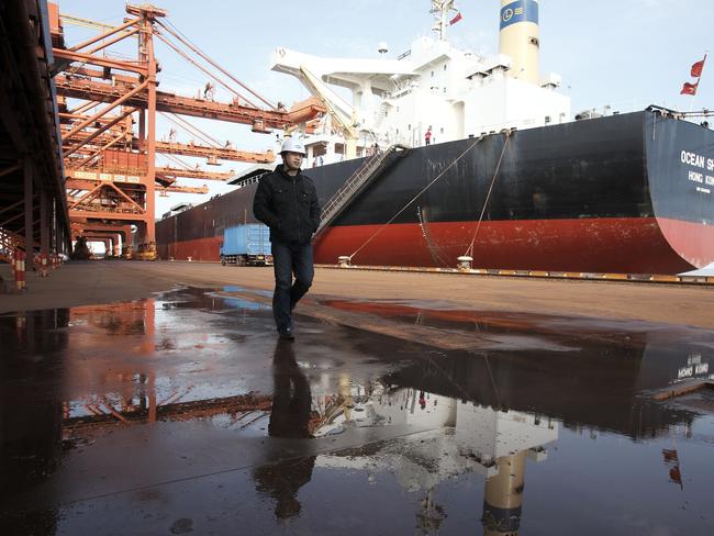 A man walks near a bulk carrier cargo ship docked at an iron-ore transfer and storage center operated by the Shanghai International Port Group in Shanghai, China on 26 January 2010.   Xxx at the Yangshan deep-water port in Shanghai, China, on Tuesday, Jan. 26, 2010. Photographer: Qilai Shen/Bloomberg