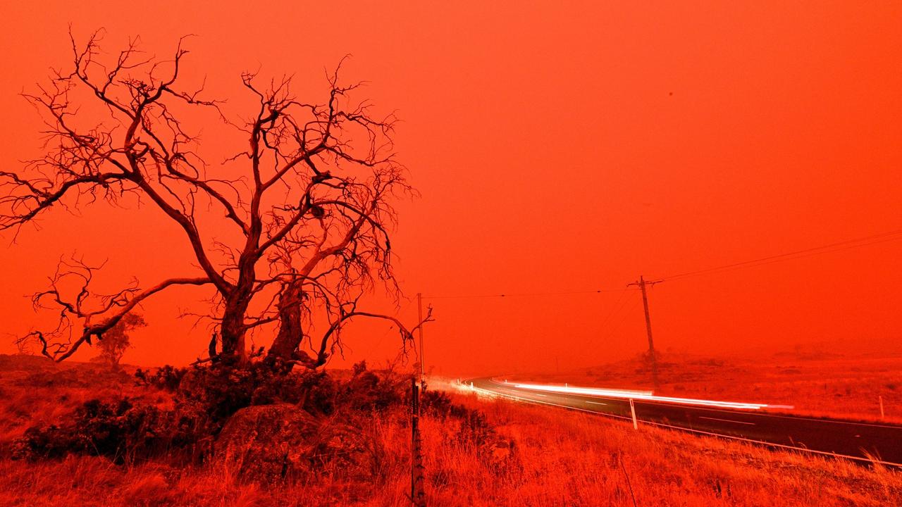 TOPSHOT - A long exposure picture shows a car commuting on a road as the sky turns red from smoke of the Snowy Valley bushfire on the outskirts of Cooma on January 4, 2020. - Up to 3,000 military reservists were called up to tackle Australia's relentless bushfire crisis on January 4, as tens of thousands of residents fled their homes amid catastrophic conditions. (Photo by SAEED KHAN / AFP)