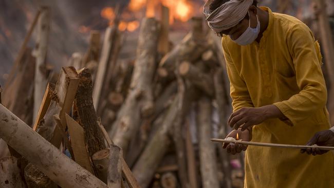 A priest lights a wooden stick as he prepares to perform the last rites of a patient who died of COVID-19 during a mass cremation in New Delhi, India. Picture: Anindito Mukherjee/Getty Images