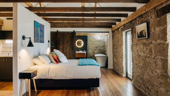 Triabunna Barracks’ lovely upstairs Loft suite, featuring a comfy kingsize bed with crisp white linens and cosy mohair throw, freestanding bath and original features such as thick sandstone walls and exposed rafters. Picture: Adam Gibson