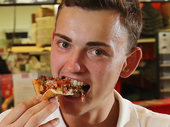 Dominos Cairns City has been voted in the top three restaurants in Cairns for the third year running by international tourists. German backpacker Henrik Bertz bites into the Deluxe pizza. PICTURE: BRENDAN RADKE