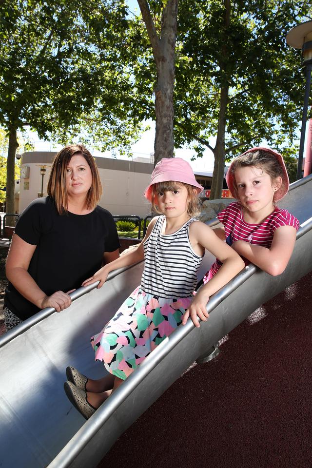 Marie Sulda of Seaford Rise with her daughters Geneva 6 (left) and Sienna 8 (right) on a slippery dip at the playground at Ramsay Place, Noarlunga Centre. Youngsters using a metal slide installed as part of Onkaparinga CouncilÕs $1.3m nature playground at Noarlunga risk being scolded during scorching heat, parents say. Southern suburb families are also calling on the council to install a shade cloth over the slide to keep it cool during extreme summer temperatures. 27/11/16 Picture: Stephen Laffer
