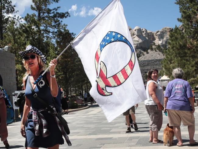 (FILES) In this file photo taken on July 1, 2020 A Donald Trump supporter holding a QAnon flag visits Mount Rushmore National Monument in Keystone, South Dakota. - Twitter has removed more than 7,000 accounts linked to the "QAnon" movement over abuse and harassment concerns, saying July 21, it will limit the spread of conspiracy theories by its supporters. (Photo by SCOTT OLSON / GETTY IMAGES NORTH AMERICA / AFP)