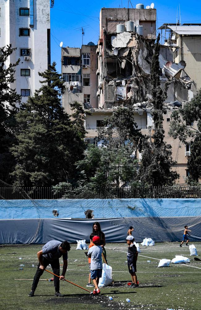 Residents clear the rubble in a football field facing the building that was hit a day earlier in an Israeli strike in Beirut's southern suburbs, on July 31. Picture: AFP