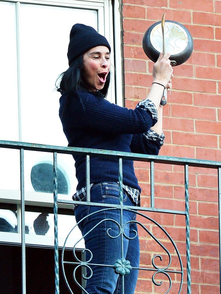 Sarah Silverman cheers on essential workers from her fire escape in New York on Easter Saturday. The comedian banged a pan with a wooden spoon and spoke through a green bullhorn.