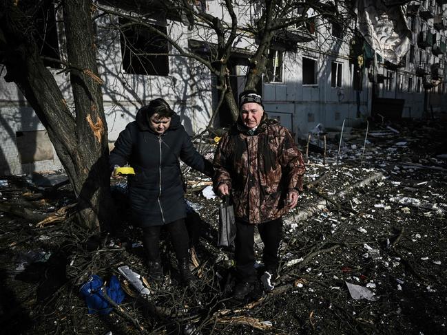 People walk past the body of a relative outside a destroyed building after bombings on the eastern Ukraine town of Chuguiv. Picture: AFP