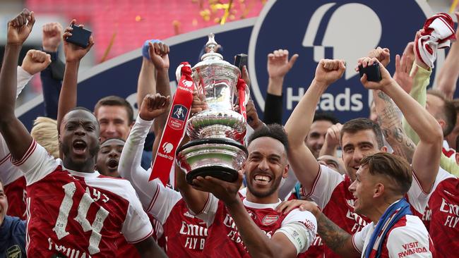 Arsenal’s Gabonese striker Pierre-Emerick Aubameyang holds the FA Cup trophy as his teammates celebrate their victory over Chelsea at Wembley. Picture: AFP