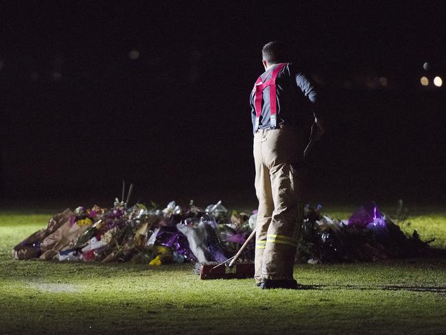 Firefighters clean graffiti painted at the memorial site of murdered Melbourne comedian Eurydice Dixon at Princess Park in Melbourne, Monday, June 18, 2018. Ms Dixon's body was found at the park in the early hours of Wednesday morning. Her accused killer, Jaymes Todd, has been charged with rape and murder. (AAP Image/Ellen Smith) NO ARCHIVING