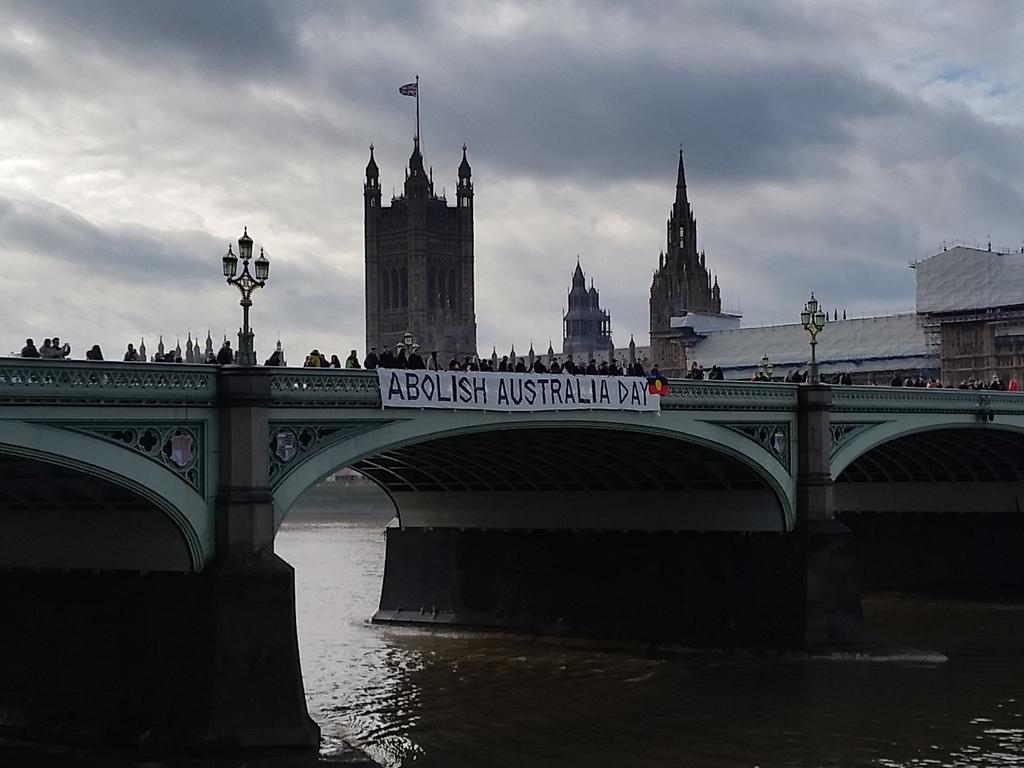 Anti-Australia Day protesters hold a banner saying "Abolish Australia Day" over the side of the Westminster Bridge in London. Picture: AAP