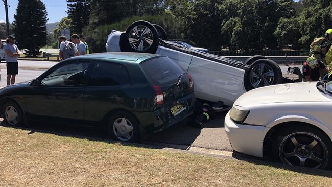 Emergency services work to remove an injured elderly driver from his overturned car on Barrenjoey Rd, Avalon Beach. Picture: WWW.MATRIXNEWS.COM.AU.