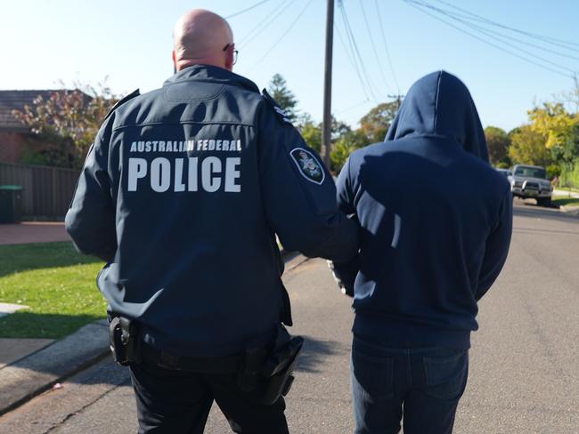 Jay Je Yoon Jung is led away as police begin the search of his Narwee home. Picture: AFP