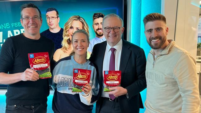 Stav Davidson, Abby Coleman, Prime Minister Anthony Albanese and Matt Acton from Brisbane's B105 radio morning show with three sample packets of the new brown snake lolly they campaigned for, designed as a tribute to the Brisbane river. Picture: Supplied