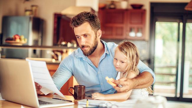 Close up of a father checking his financials while his daughter has breakfast and while he is working from home. Picture: iStock.