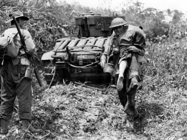 A wounded Australian soldier is carried from the forward area as Matilda tanks advance on the Japanese-held village of Sattelberg in 1943. Picture: Department of Information G940.542