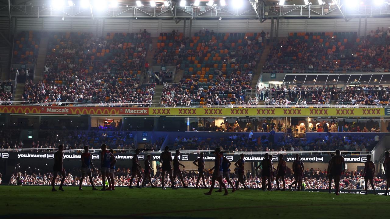 Players wait on field as power goes out during the round two AFL match between Brisbane Lions and Melbourne Demons at The Gabba. (Photo by Chris Hyde/Getty Images)