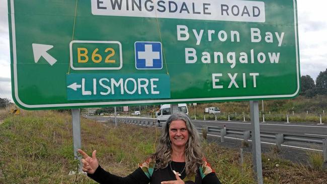 Greens Lismore council candidate Vanessa Grindon-Ekins with a cardboard 'Lismore and Villages' sign at Ewingsdale Road.