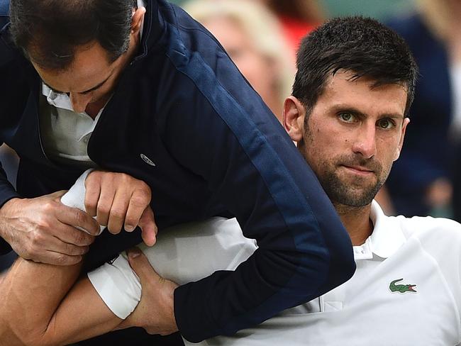 TOPSHOT - Serbia's Novak Djokovic gets some medical attention on court in a break between games against France's Adrian Mannarino during their men's singles fourth round match on the eighth day of the 2017 Wimbledon Championships at The All England Lawn Tennis Club in Wimbledon, southwest London, on July 11, 2017. / AFP PHOTO / Glyn KIRK / RESTRICTED TO EDITORIAL USE