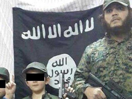 Khaled Sharrouf and boys believed to be his stand in front of the Islamic State flag in an image posted on Twitter. Source: Supplied