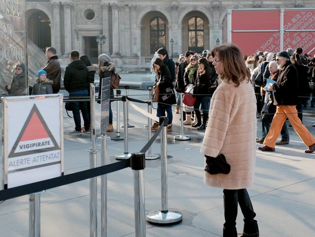 A tourist reads the placard " VIGIPIRATE (security plan) Alert Attacks" in front of the Louvre museum in Paris, Saturday, Jan. 17, 2015. Tourism officials couldn’t give figures of the number of sightseers in the immediate aftermath of the terrorist attacks that killed 17 people in Paris, but visits by The Associated Press to major sites and interviews with vendors indicated an initial drop in visitors. Among the tourists that were still braving visits, many took comfort in the extra security presence. With 10,500 troops deployed across the country, including 6,000 in the Paris region alone, the security operation put in motion after the attacks is the most extensive on French soil in recent history. (AP Photo/Jacques Brinon)