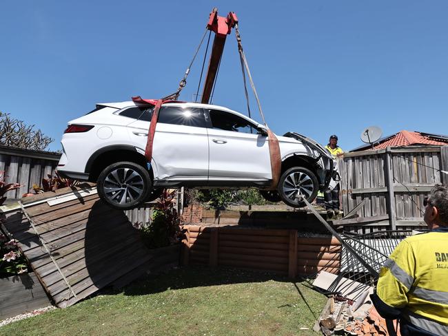 Tow truck and crane drivers work to lift the the BYD car that smashed through a garden at no.16 Wattlebrush Grove , went over a retaining wall and ended up back of 60 Crestwood Dr. Picture Glenn Hampson