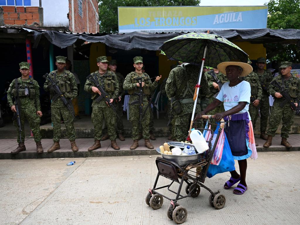 Colombian marines patrol next to a street vendor during security operations before the arrival of Prince Harry and Meghan Markle in San Basilio de Palenque, Colombia. Picture: AFP