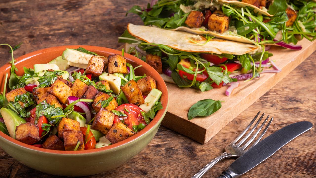 Vegan salad bowl with vegetables and fried tofu (left) and tacos with vegetable salad.