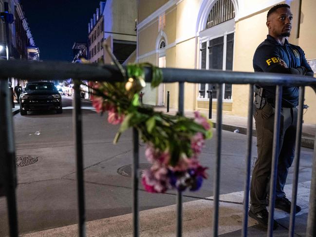 A member of the FBI looks on near a bouquet of flowers tied to a fence, a block from Bourbon Street. Picture: AFP