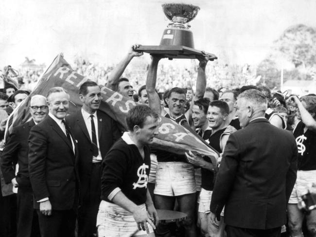 Neil Kerley holding the Thomas Seymour Hill Memorial trophy with teammates after victory by South Adelaide in SANFL grand final in 1964.