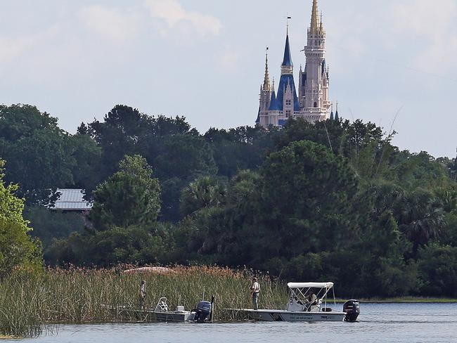 In the shadow of the Magic Kingdom Florida Fish and Wildlife Conservation Officers search for the body of a young boy Wednesday, June 15, 2016 after the boy was snatched off the shore and dragged underwater by an alligator Tuesday night at Grand Floridian Resort at Disney World in Lake Buena Vista, Fla. (Red Huber/Orlando Sentinel via AP)