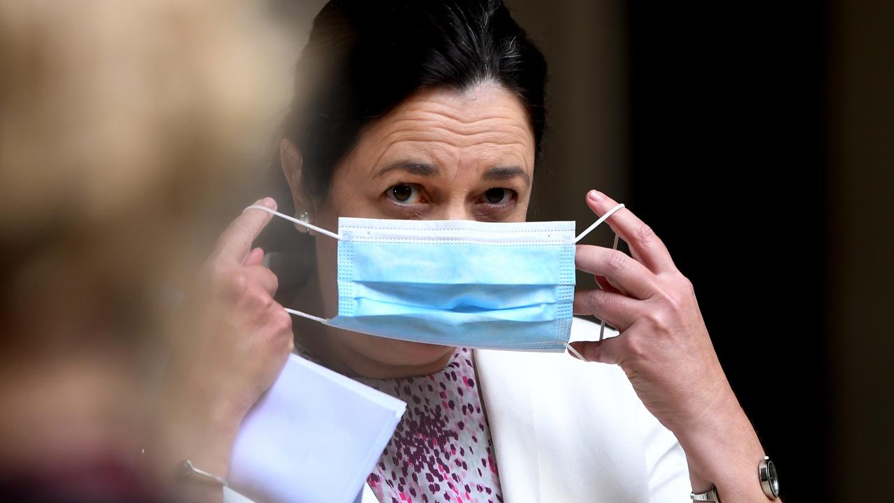 Queensland Premier Annastacia Palaszczuk is seen at a press conference putting on a mask today. Photo: Dan Peled