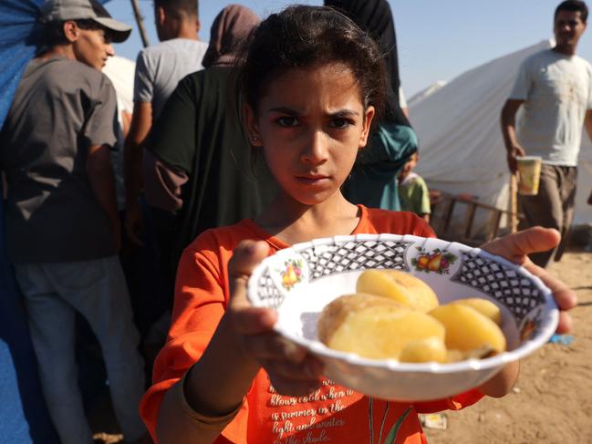 A Palestinian girl, who fled her home with her family amid Israeli strikes, shows her plate of food at a UN centre. Picture: AFP