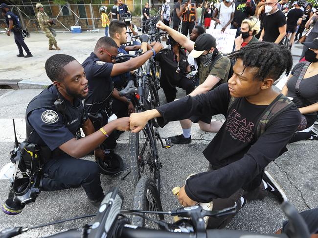 Atlanta Police Officer J. Coleman, left, and protester Elijah Raffington, of Sandy Springs, fist bump while an Atlanta Police bicycle unit blocking Marietta Street at Centennial Olympic Park Drive. Picture: Curtis Compton/Atlanta Journal-Constitution