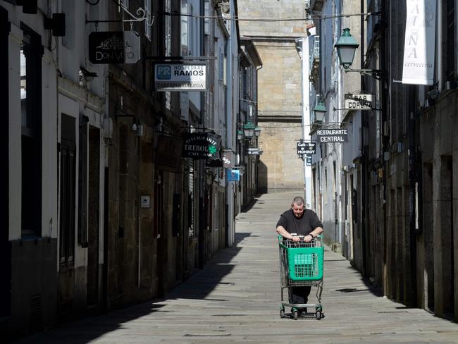 A man pushes an empty trolley in Santiago de Compostela in Spain after regional authorities ordered all shops in the region be shuttered from today through March 26, save for those selling food, chemists and petrol stations, in order to slow the coronavirus spread. Picture: AFP