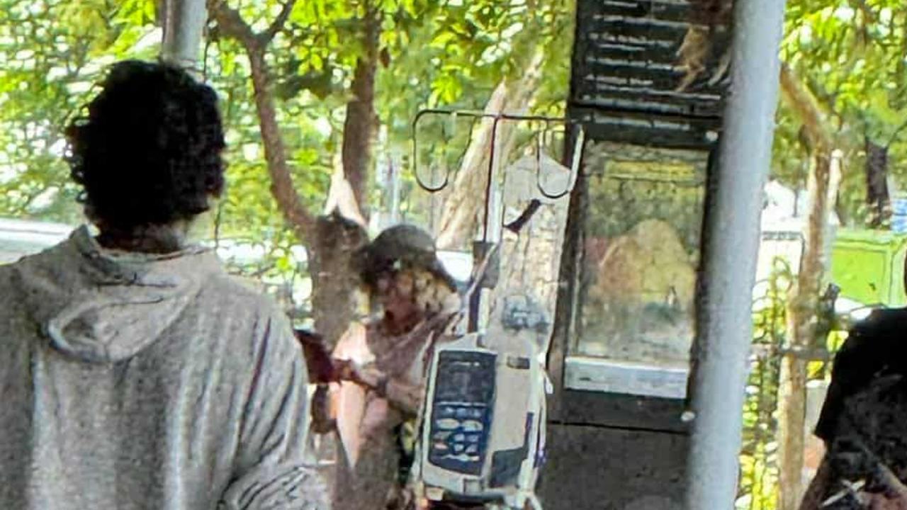 A Cairns Hospital patient hooked to a drip walks through the Cairns CBD.