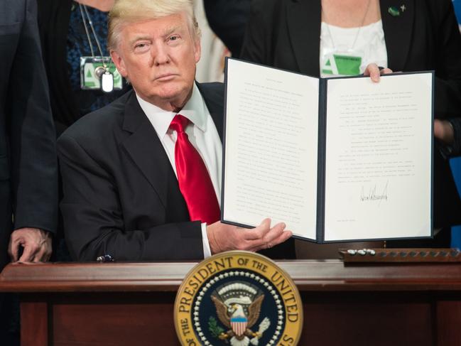 (FILES) US President Donald Trump signs an executive order to start the Mexico border wall project at the Department of Homeland Security facility in Washington, DC, on January 25, 2017. While the new US president has shown a capacity to change, both his tone and his positions, he has been unable to show the world a "new" Trump, with a steady presidential style and a clearly articulated worldview. As the symbolic milestone of his 100th day in power, which falls on April 29, 2017, draws near, a cold, hard reality is setting in for the billionaire businessman who promised Americans he would "win, win, win" for them. At this stage of his presidency, he is the least popular US leader in modern history (even if his core supporters are still totally behind him.) / AFP PHOTO / NICHOLAS KAMM / TO GO WITH AFP STORY, US-politics-Trump-100days