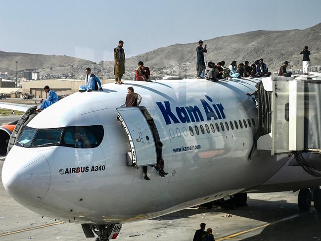 Afghan people climb atop a plane as they wait at the airport in Kabul on Monday, after a stunningly swift end to Afghanistan's 20-year war, as thousands of people mobbed the city's airport trying to flee the group's feared hard line brand of Islamist rule. Picture: Wakil Kohsar/AFP