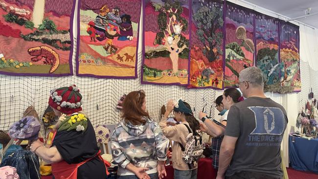 Attendees try on beanies beneath intricate displays at the 2023 Alice Springs Beanie Festival. Picture: Laura Hooper.