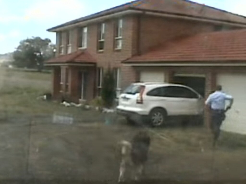 Senior Constable Christopher Hurtak, gun drawn, runs into the garage.