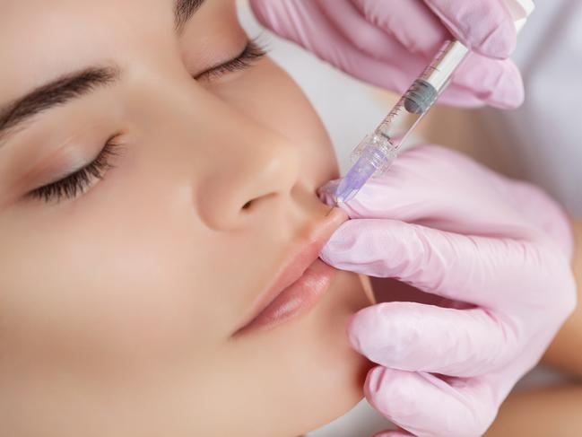 The doctor cosmetologist makes Lip augmentation procedure of a beautiful woman in a beauty salon.Cosmetology skin care.