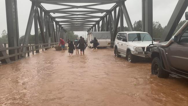 People trudge through flood water at the Ballina Street Bridge to meet a boat at the other end in South Lismore on February 28, 2022.