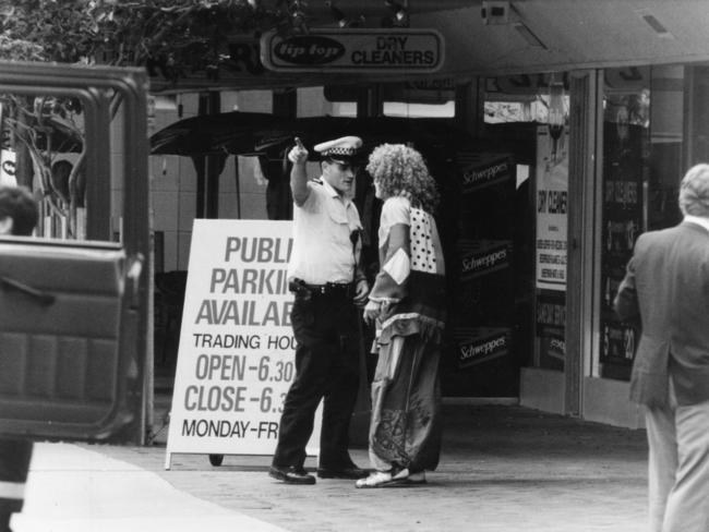 A police officer sends a clown away from a blocked street in 1994.