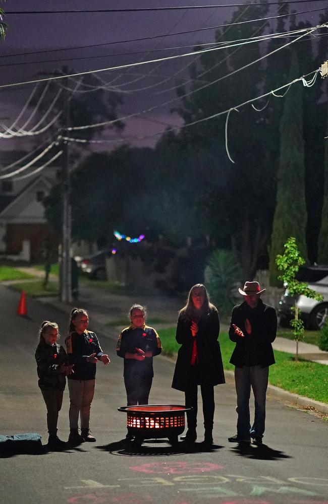 A family in Clara St, Macleod stands around a flame at dawn this morning. Picture: AAP