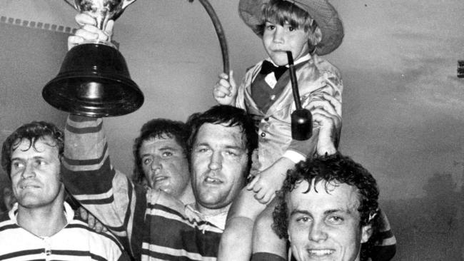 The 1976 Brisbane Rugby League President's Cup winners, Ian Dauth, Peter McNamara, captain David Wright with the trophy and John Herlihy. The team leprechaun mascot is Darren Paterson.