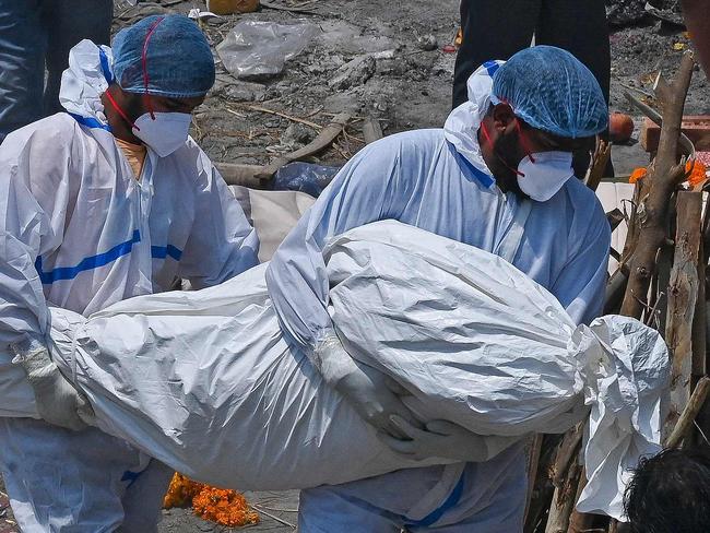 TOPSHOT - Family members and ambulance worker wearing PPE kit (Personal Protection Equipment) carry the bodies of the patients who died of the Covid-19 coronavirus at a cremation ground in New Delhi on April 27, 2021. (Photo by Prakash SINGH / AFP)